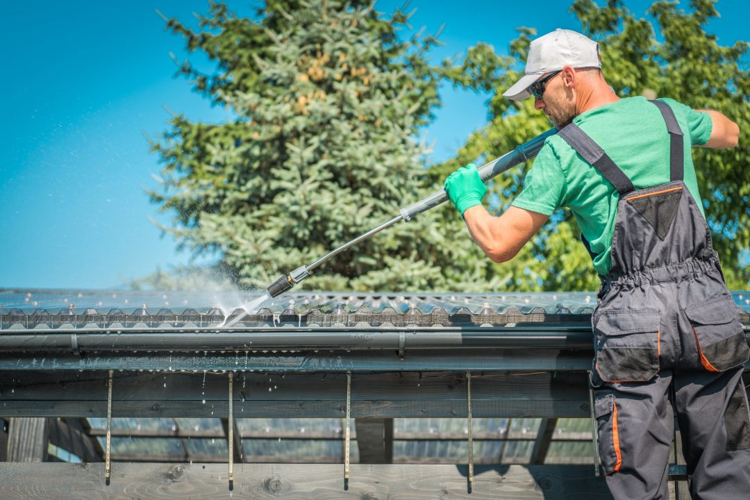 A man is cleaning roof with water gun
