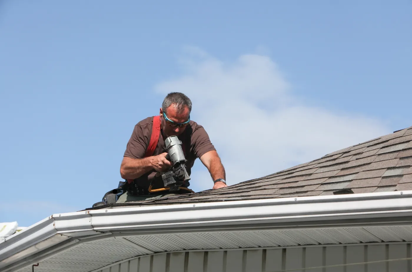 A worker wearing glasses is fixing shingles