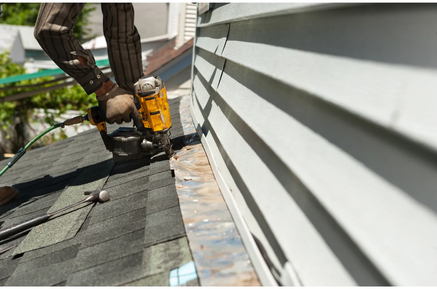 A roofer is fixing shingles with machine