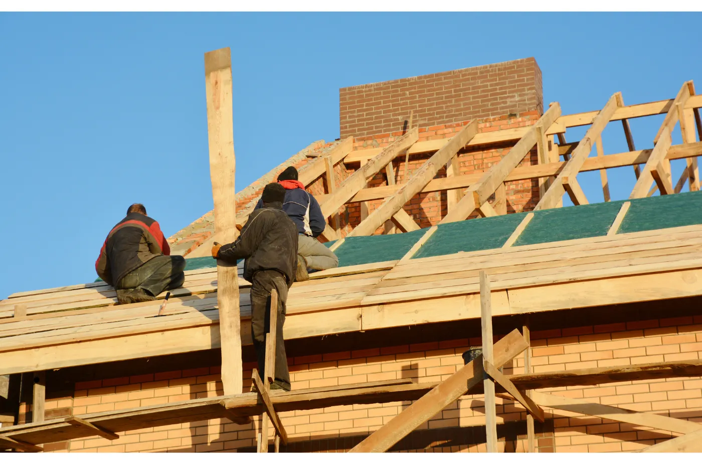Three workers are working on structure of roof