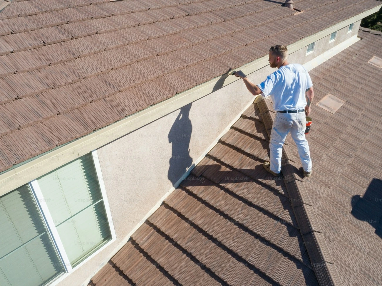 A worker is applying glue on the roof