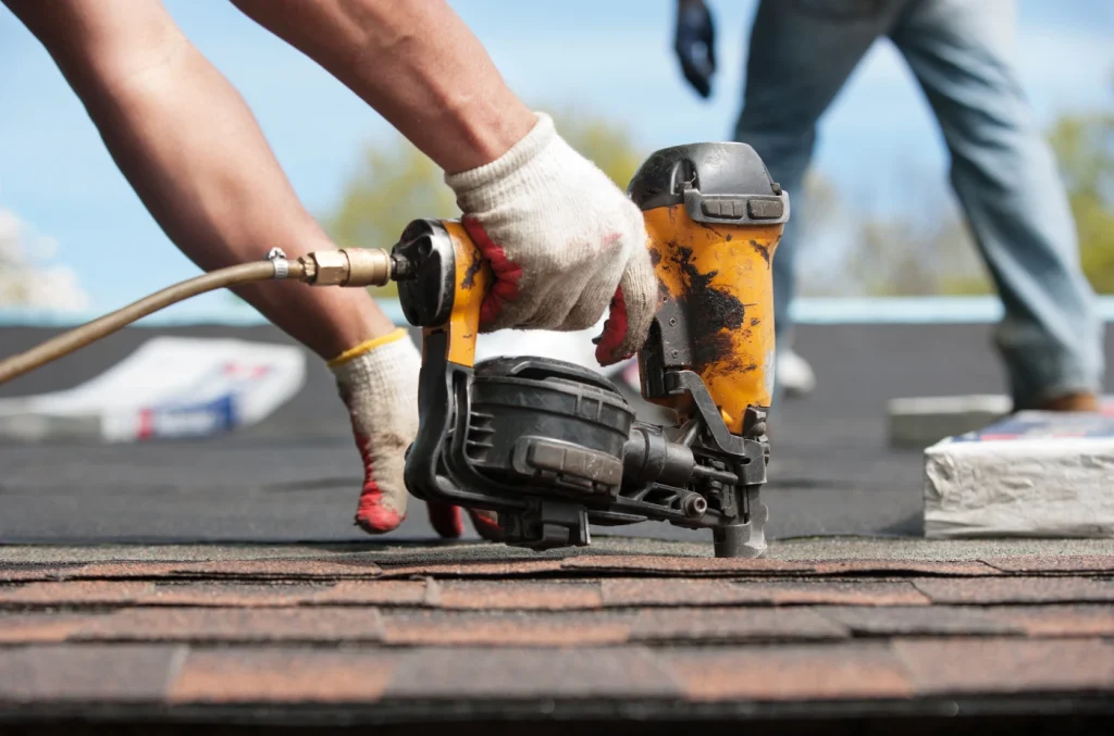 Anaheim roofers repairing asphalt shingles with power tools on a residential roof.