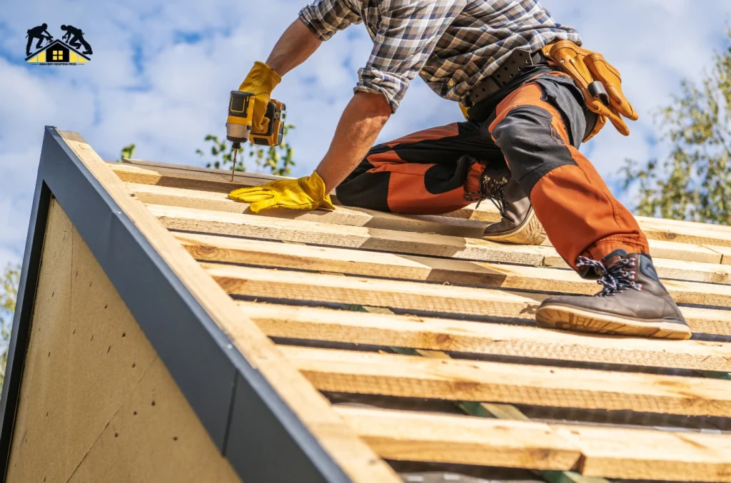 A construction worker installing wooden roof sheathing on a house roof frame.