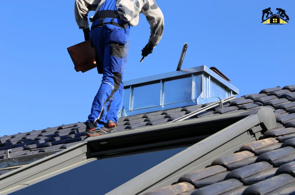 Roofer standing on a sloped roof using tools while installing roofing material under a bright blue sky.