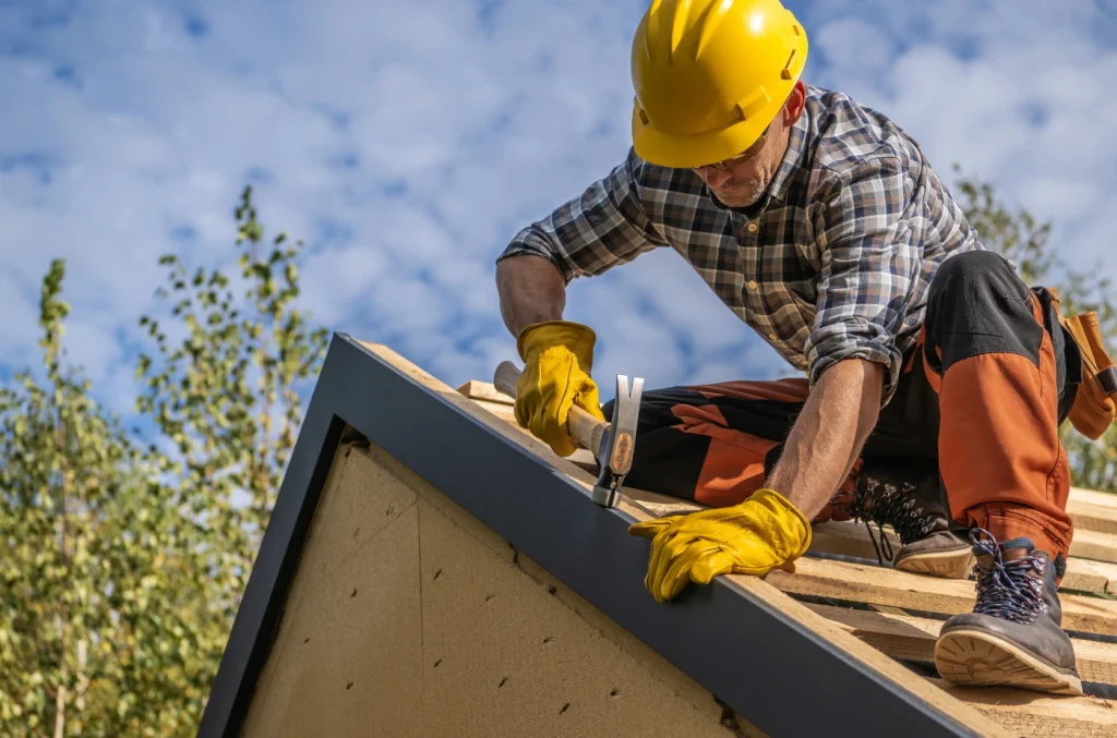 Construction worker measuring and installing a roofing panel on a house roof.